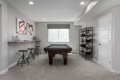 a pool table in the middle of a room with stools and shelves on either side