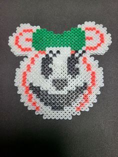 a close up of a beaded tiger head on a black surface with red, white and green beads