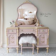 a pink vanity with a mirror and bench in front of the dresser is adorned with white fur