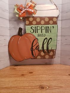 a wooden sign that says sippin'into fall with a pumpkin on the front