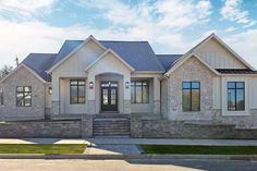 a large white house with stone walls and steps leading up to the front door on a sunny day