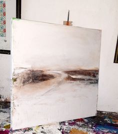 an abstract painting is being displayed on the easel in front of a white wall