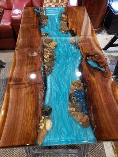 a table made out of wood and glass with blue water running through the center piece