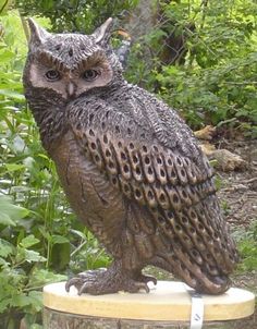 an owl statue sitting on top of a wooden stump