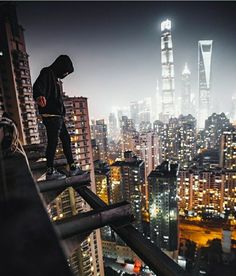 a man standing on top of a tall building in the middle of a city at night