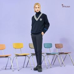 a woman standing in front of several chairs wearing a black sweater and pants with white piping