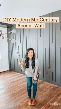 a woman standing in front of a wall holding a light bulb and pointing at it