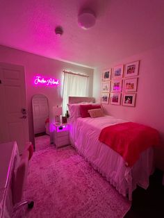 a bedroom with pink lighting and pictures on the wall above the bed, along with an area rug