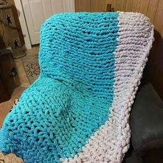 a blue and white crocheted blanket sitting on top of a couch