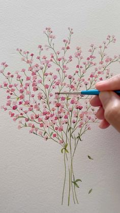 someone is drawing flowers on the wall with pencils and watercolor paper, while holding a pen in their left hand