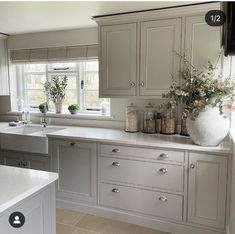 a kitchen with white cabinets and flowers in vases on the window sill over the sink