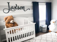 a baby's room with striped walls and white crib, teddy bear and penguin