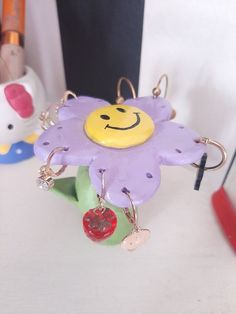 a purple flower with a smiley face on it's keychain sitting on a table