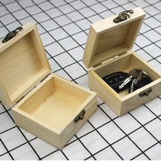 two small wooden boxes with scissors inside on a tiled floor, one opened and the other closed