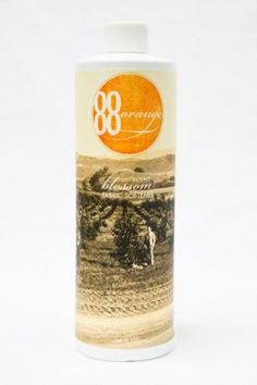 a bottle of wine with an orange label on the front and bottom, sitting on a white surface