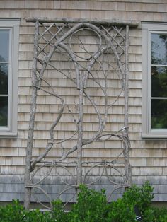 an old wooden window frame sitting on the side of a building next to some bushes