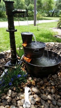 an outdoor fountain with three buckets on it and water running from the top to the bottom