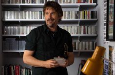 a man standing in front of a bookshelf holding an award