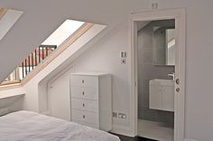 an attic bedroom with slanted ceilings and white furniture