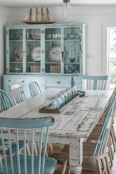 a dining room table with blue chairs and china cabinet in the backround area