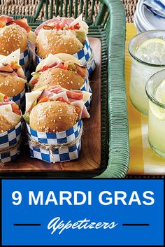 many sandwiches are wrapped in blue and white checkered paper on a tray next to drinks