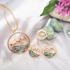 Dive into a world of whimsy with our Dolphin Dance Abalone Earrings. Immerse yourself in the playful energy of leaping dolphins over the iridescent waves of abalone shells. The intricate design captures the fluidity of the ocean, while the shimmering abalone adds a touch of enchantment. These earrings are adorned with delicate gold detailing, creating a harmonious balance between elegance and the carefree spirit of the sea. Let these earrings be a reminder of joy, freedom, and the beauty that dances beneath the waves. Abalone shells & sparkle gems Fish-hook drop earrings Size: 1" W x 2.5" L Jewelry pouch included (color may differ) In interests of hygiene and for your protection, we cannot accept returns on earrings. Aloha Dress, Hawaiian Necklace, Take A Leap, Shell Mirror, Aloha Print, Abalone Earrings, Comfy Sandals, Gold Rope Chains, Abalone Shell