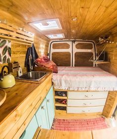 the interior of a small camper with wood paneling and white bed in it