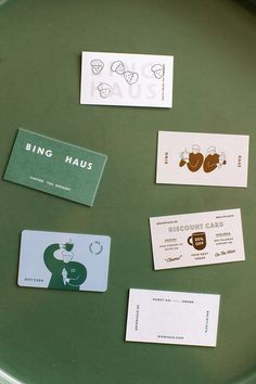 some business cards are sitting on a green plate with white tags attached to them that read bing haus