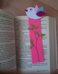 an open book with a bird on top of it next to a pink bookmark