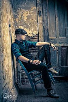 a man sitting on top of a chair in an alleyway next to a building