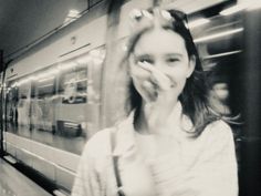 a woman standing in front of a train at a station with her hand on her face