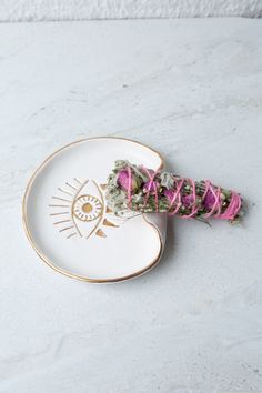 a white and gold plate with pink flowers in it on a marble counter top,