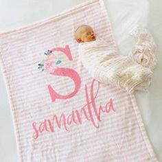 a baby wrapped in a pink and white striped blanket with the letter s on it