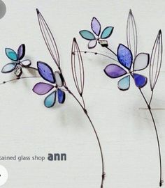 three purple and blue glass flowers on a white background with the words stained glass shop ann