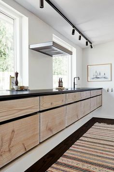 a kitchen with wooden cabinets and black counter tops in front of a large open window