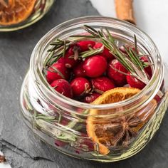 a glass jar filled with cranberry oranges and rosemary garnishes