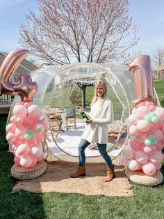 a woman standing in front of an inflatable bubble house with balloons on the ground