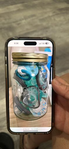 a person holding up a cell phone with an image of various items in the jar