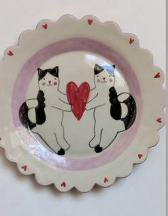 a plate with two cats holding a heart