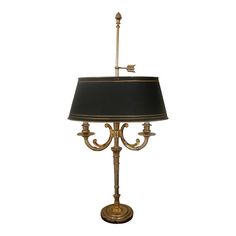 a table lamp with a black shade on the top and gold trimmings around it