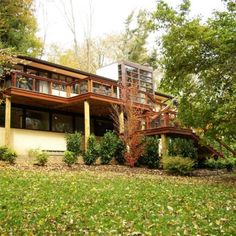 a large house in the woods with lots of trees and leaves on the ground around it