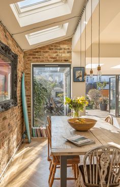 a dining room table with chairs and a skylight in the ceiling above it is surrounded by brick walls