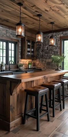 a kitchen with wood floors and stone walls, two stools at the bar counter