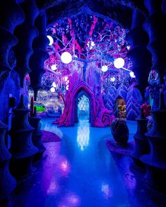 the inside of a building with blue and purple lights on it's walls, in front of a tree