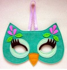 a green mask with pink flowers and leaves on the eyes is hanging from a string