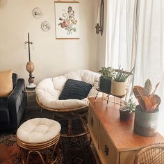 a living room filled with furniture and plants on top of a wooden table in front of a window