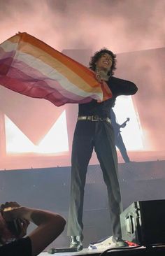 a man standing on top of a stage with a flag in front of his face