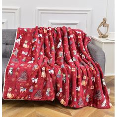 a red blanket with christmas decorations on it sitting on top of a couch next to a chair