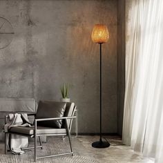 a living room with a couch and chair next to a lamp on the floor in front of a concrete wall