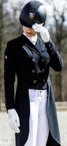 a woman in white riding pants and a black jacket with a helmet on her head